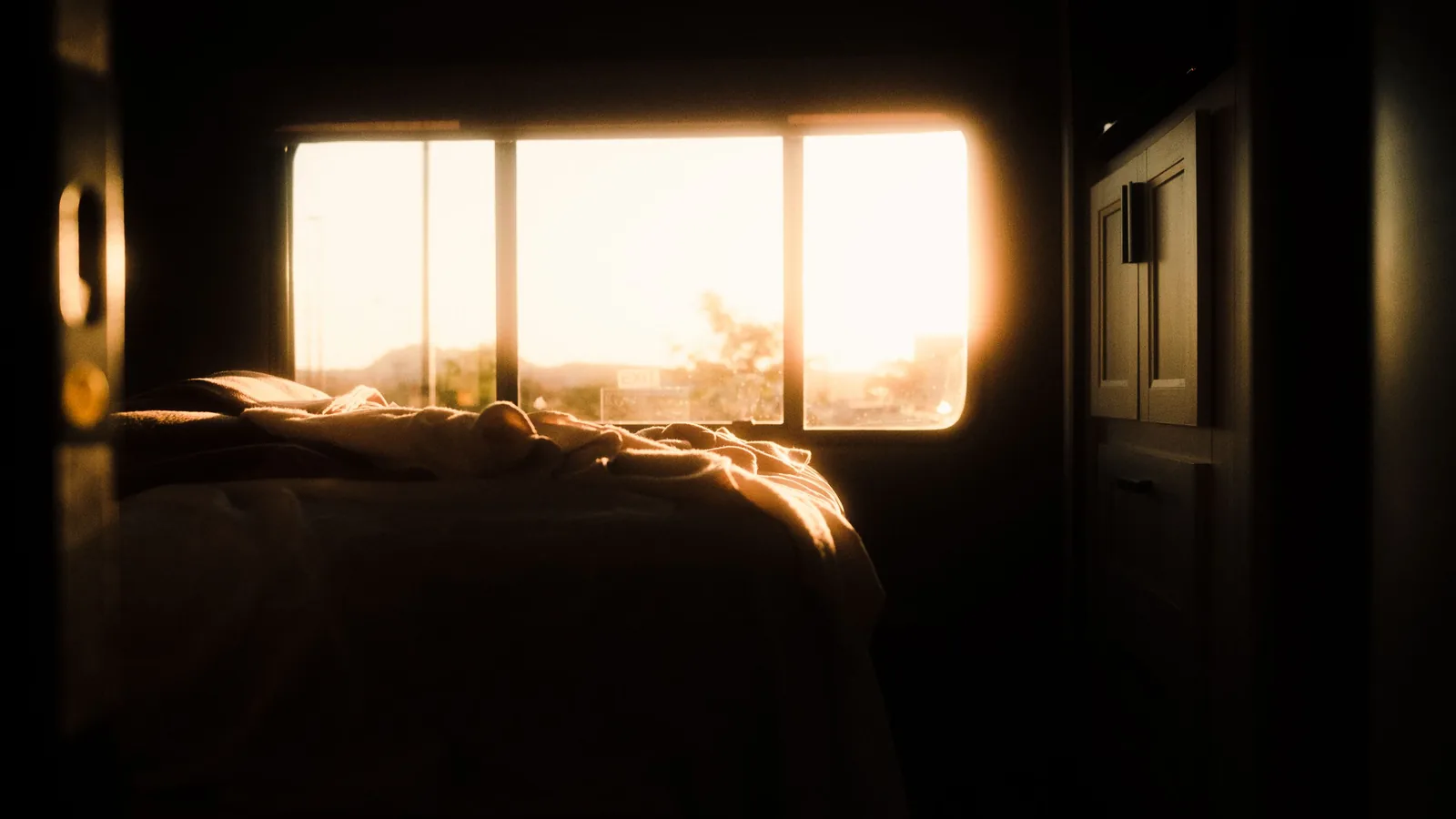Tranquil bedroom interior bathed in warm sunrise light through the window, creating a serene atmosphere.