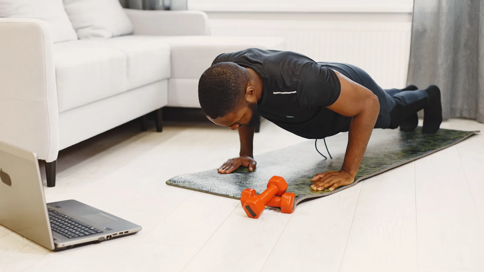 A man doing push-ups on a mat in a modern living room, focusing on home workouts.
